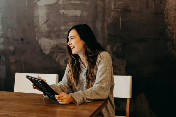 Woman holding tablet sitting down.